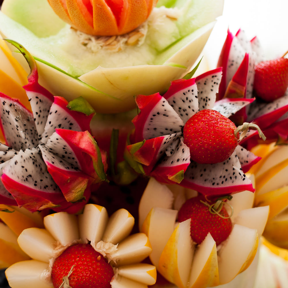 Dragon fruit cut into stars and set among carved melon petals and strawberries on a tiered display.