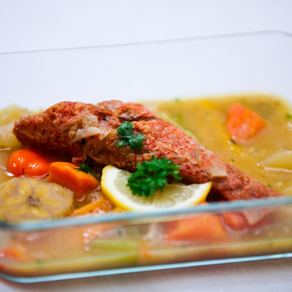 A whole red snapper in broth with green banana, carrot, scotch bonnet and lemon, Antiguan style.