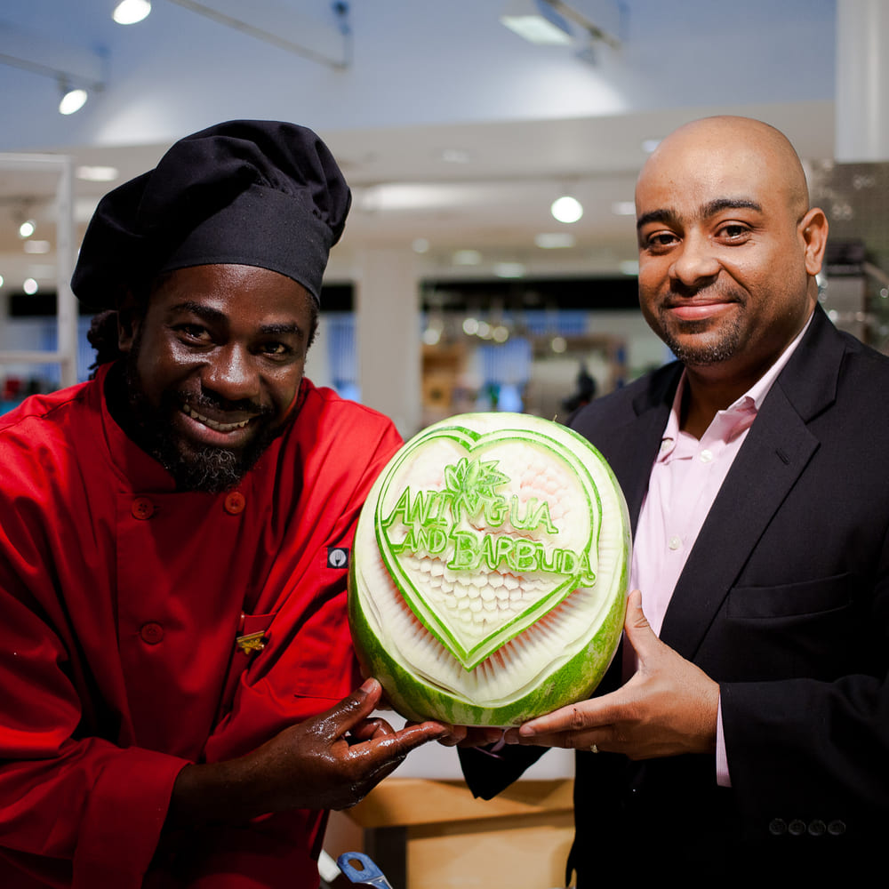 Chef Melvin Myers and Franz DeFreitas holding a watermelon carved with Antigua and Barbuda in a heart.