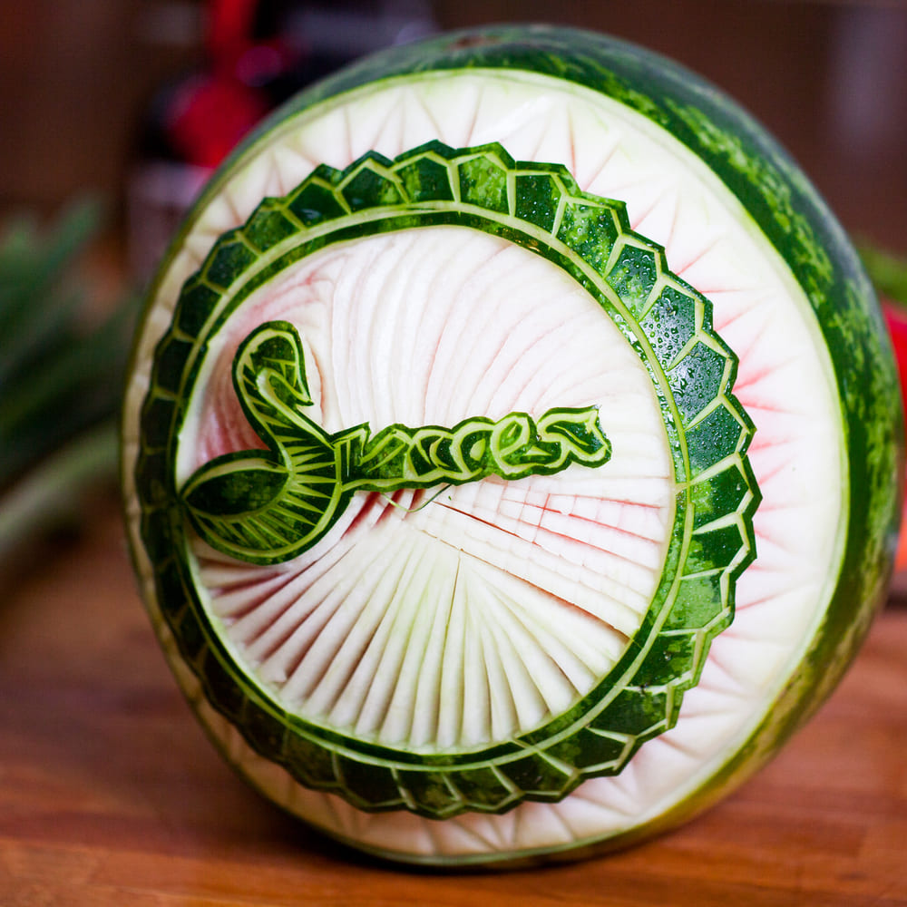 The Success Catering swan logo carved into the rind of a watermelon on a wooden kitchen bench.